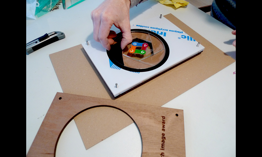 De award bestaat uit enkele lagen perspex en hout.